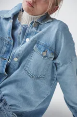 Sobrecamisa celeste de denim con bolsillos frontales con solapa y cierre abotonado.