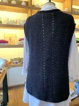 Chaleco negro tejido a mano en dos agujas con hilado 100% baby alpaca, ligeramente oversize, de hombros anchos y cuello tipo bote, con puntos calados en frente y espalda y tajos a los lados en el bajo.