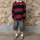 Buzo de manga larga con cuello polo blanco, a rayas horizontales color ladrillo y azul marino, con logo bordado en el pecho.