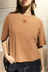 Remera negra de algodón con corte cuadrado, cuello redondo y logo bordado en color naranja.