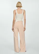 Pantalón color beige de corte wide leg, tiro medio y cinturón ajustable con hebilla circular.