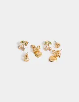 Set de tres pares de aros pasantes dorados: un par de aros con forma de cerezas con strass, un par de aros con forma de corazón con moño y un par de aros redondos con strass.