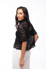 Camisa blanca de encaje con cuello clásico, cierre frontal con botones y mangas cortas.