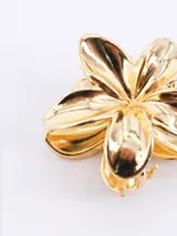 Pinza de pelo dorada con forma de flor de cinco pétalos.