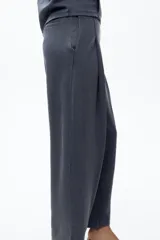 Pantalón color arena de tiro medio con cintura elástica, bolsillos laterales ocultos y pinzas en el delantero.