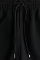 Short negro de felpa liviana de mezcla de algodón, con elástico revestido en la cintura, cordón para ajustar y bolsillos discretos en las costuras laterales.