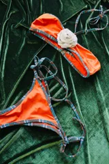 Conjunto de bikini negro con estampado difuminado en blanco y negro en los bordes y tiras. El corpiño es bandeau con detalle de flor negra en el centro.