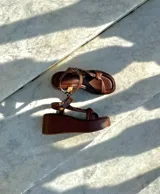 Sandalias doradas con plataforma, tiras cruzadas y hebilla al tobillo.