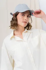 Gorra de béisbol color amarillo pastel, con visera curva y logo de Peach bordado en el frente. Ajustable en la parte trasera.