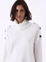 Sweater blanco de punto con cuello alto y botones decorativos en los hombros.