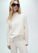 Sweater color crema de tejido de punto fino, cuello alto y corte oversize.