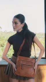 Bandolera negra de símil cuero con dos bolsillos frontales con cierre y detalles de tachas metálicas. Incluye un bolsillo trasero, tres bolsillos internos y correa larga regulable.