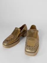 Mocasines dorados de cuero con suela beige.