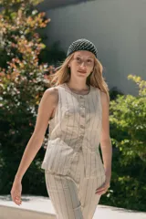 Chaleco color crema a rayas verticales negras, entallado y con leve abertura en la parte baja.