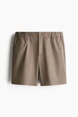 Short color marrón claro, de corte recto y largo a la rodilla. Presenta cintura con elástico en los laterales, cierre con botón, bolsillos al bies y bolsillos traseros ribeteados con botón.