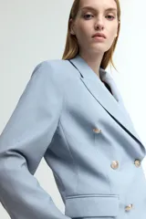 Blazer celeste de doble botonadura con solapas de pico, hombreras finas, bolsillos delanteros ribeteados con solapa y puños abotonados con abertura decorativa. Forrado.