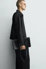Bolso tipo shopper fabricado en cuero negro. Tiene un bolsillo interior plano con cierre mediante cremallera y asas de cuero.