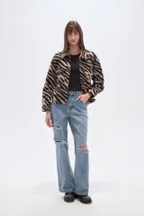 Campera estilo camisa (shacket) cropped, con cuello, cierre frontal y dos bolsillos con tapa en el pecho. Presenta un estampado de cebra en tonos beige y negro.