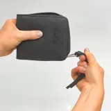 Billetera negra de cuero sintético con cierre alrededor y logo de la marca en el frente.