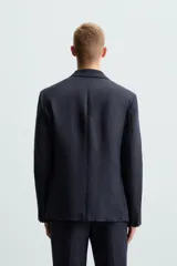 Blazer azul marino de lino con corte regular fit, cuello con solapas de muesca, manga larga con puños abotonados, bolsillo de vivo en el pecho, bolsillos de solapa en la cadera, bolsillo interior, aberturas en la espalda y cierre frontal de botonadura.