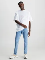 Jeans celeste de corte slim fit, tiro medio y pierna cónica. Diseño clásico de cinco bolsillos, con cierre de botón y cremallera.