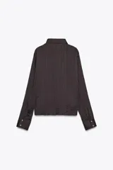 Camisa oversize color marrón oscuro confeccionada en tejido satinado con efecto arrugado, cuello solapa, manga larga con puños y cierre frontal con botones metálicos.