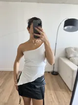 Top blanco de lycra, con un solo hombro y corte irregular en la parte inferior.