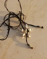 Collar artesanal con dije de flor plateada, realizado con hilo de seda natural teñido a mano.