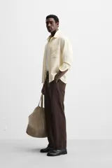 Camisa color crema de corte relaxed fit, confeccionada en tejido con mezcla de viscosa. Tiene cuello solapa, manga larga con puños abotonados, bolsillo de parche en el pecho y cierre frontal con botones.