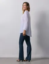 Blusa blanca de manga larga con cuello a la base y escote en V con botones. Terminación de manga con elástico.
