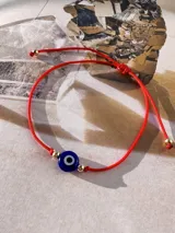 Pulsera roja de hilo con cierre de nudo macramé, con dije de ojo turco azul y cuentas doradas.