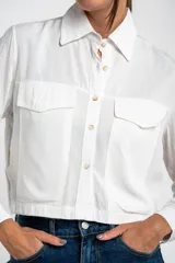 Camisa crop de 100% viscosa, color blanco, con botones y dos bolsillos frontales.