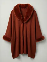 Ruana tejida color terracota, de corte amplio y asimétrico, con cuello y puños adornados con apliques de piel sintética del mismo tono.