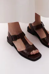Sandalia marrón con textura tipo cocodrilo, con tiras en forma de T y hebilla lateral.