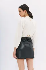 Minifalda negra de cuero sintético, corte recto, con bolsillos laterales y traseros.