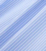 Camisa celeste con rayas verticales blancas, de corte amplio y manga larga.