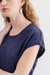 Remera de lino gris melange con tachas termo fijadas, de corte amplio y mangas cortas.