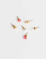 Set de tres pares de aros pasantes: un par de aros con forma de corazón dorado, un par de aros con forma de flor roja con strass y un par de aros de perlas.