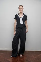 Pantalón negro de algodón con pretina elástica, bolsillos laterales y pinzas horizontales en las rodillas.