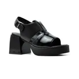 Sandalias de cuero sintético negro con plataforma y tacón bloque. Presentan una tira ancha sobre el empeine con aberturas geométricas y pulsera con hebilla al tobillo.