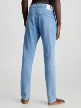 Jeans celeste de corte slim fit, tiro medio y pierna cónica. Diseño clásico de cinco bolsillos, con cierre de botón y cremallera.