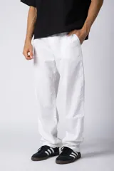 Pantalón de lino color beige, de corte recto y holgado, con cintura elastizada y cordón ajustable. Presenta bolsillos laterales amplios.