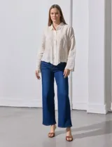 Camisa de manga larga color beige, con bordado tipo broderie, cuello con solapa y abertura central con botones.