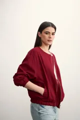 Chaqueta bomber negra con cierre frontal dorado y mangas largas con puños elásticos.