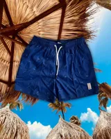 Short de baño azul con estampado de tablas de surf blancas, cintura elástica con cordón ajustable y bolsillos laterales.