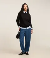 Sweater negro de punto con cuello redondo, puños y ruedo acanalados. Incluye cuello, puños y ruedo de camisa celeste a rayas.