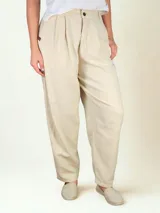 Pantalón de lino color beige, de corte holgado y pinzado, con bolsillos laterales y cierre frontal con botón.