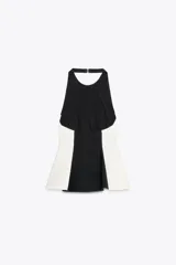Top negro con cuello halter y espalda descubierta. Presenta detalle de combinación de tejidos en contraste con laterales blancos y bajo acabado en peplum.