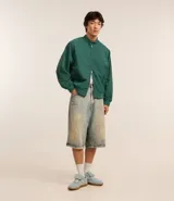 Campera bomber verde oscuro de poliéster con cuello alto con velcro, cierre por cremallera, bolsillos con solapa, manga larga ajustada y bajo ajustado.