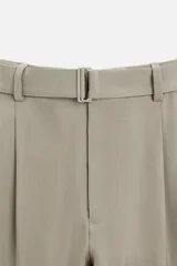 Pantalón negro de corte amplio, con pliegues frontales, bolsillos laterales y traseros de ojal. Incluye cinturón de la misma tela con hebilla metálica.